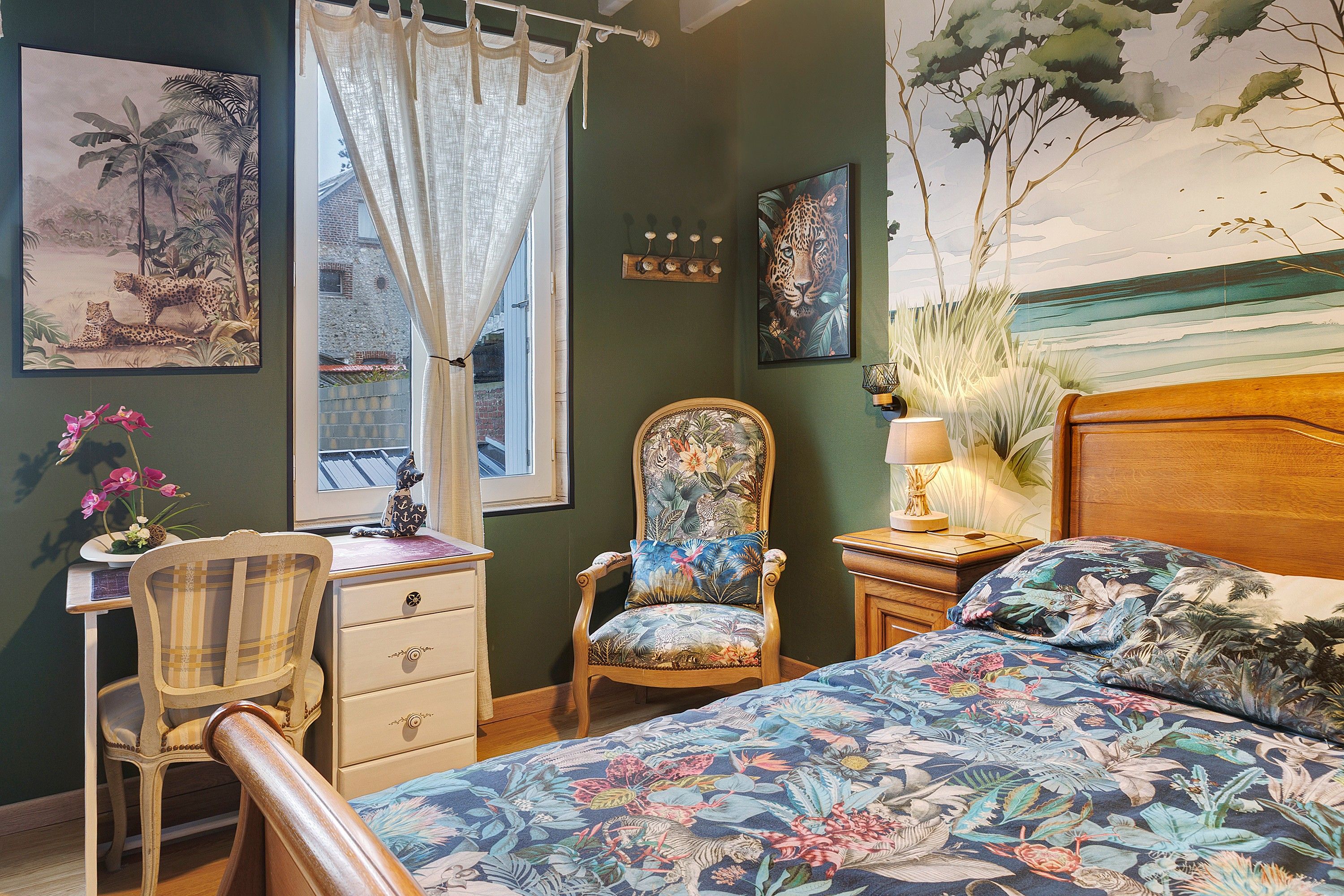 Een slaapkamer met een bed, een stoel, een bureau en een raam met gordijnen.