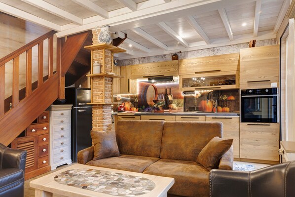 Una cocina acogedora con chimenea de piedra, armarios de madera y un refrigerador moderno.