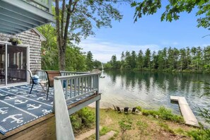 A lakeside deck with a view of the lake, a covered patio area, and outdoor furniture.