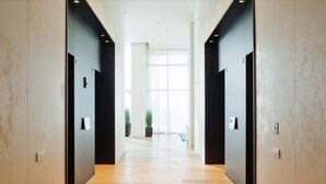A modern hallway with wooden flooring, black walls, and a large window at the end. - Elegant Tower Apt | Sea View & Parking | Mamad (Bat Yam)