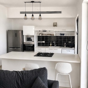 Une cuisine moderne dotée d’un îlot central, de meubles blancs et d’un pare-feu noir.