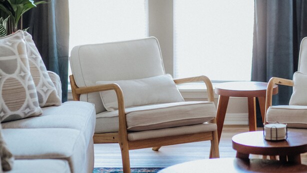 A modern living room with a white sofa, two white armchairs, a wooden coffee table, and a potted plant. - Convenient 2BR Escape | Easy Walk to MOB (Mobile)