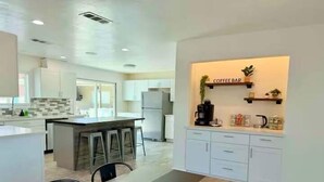 A modern kitchen with a central island, bar stools, and a coffee bar area. - Endless Summer, Pool/Theatre/Boat Parking/Walk to London Bridge! (Lake Havasu City)