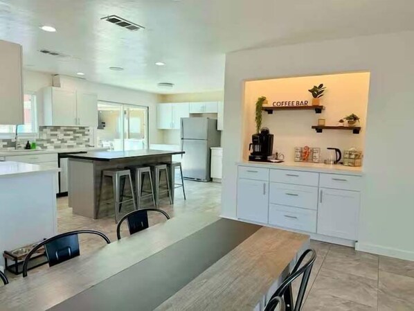Una cocina moderna con una isla central, taburetes de bar y una zona de café.