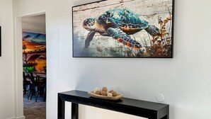 A modern interior with a black console table, a framed seahorse painting, and a ceiling light fixture. - Endless Summer, Pool/Theatre/Boat Parking/Walk to London Bridge! (Lake Havasu City)