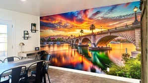 A dining area with a mural of a sunset over a river and bridge. - Endless Summer, Pool/Theatre/Boat Parking/Walk to London Bridge! (Lake Havasu City)