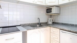 A kitchen with white cabinets, a granite countertop, a stainless steel sink, a microwave, and a coffee maker.