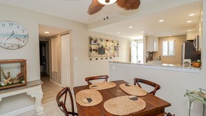 A dining area with a wooden table, four chairs, and woven placemats. - New to Rental Program! Beautiful Ocean View 3/2 at St. Augustine Beach & Tennis Club 301 (St. Augustine)