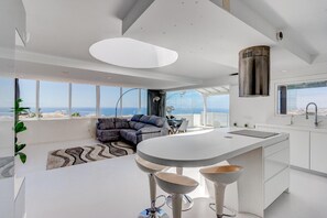 Une cuisine moderne dotée d’un grand îlot central, d’un coin repas avec un canapé et d’une vue sur la ville.