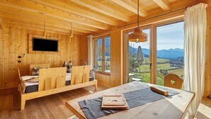 Ein Holzinnenraum mit einem Bett, einem Tisch und einem an der Wand befestigten Fernseher.