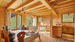 Ein Holzblockhaus mit Bett, Essbereich und Küche.