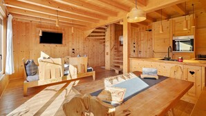Un interior de madera con un sofá, una mesa de comedor, un televisor y una zona de cocina.