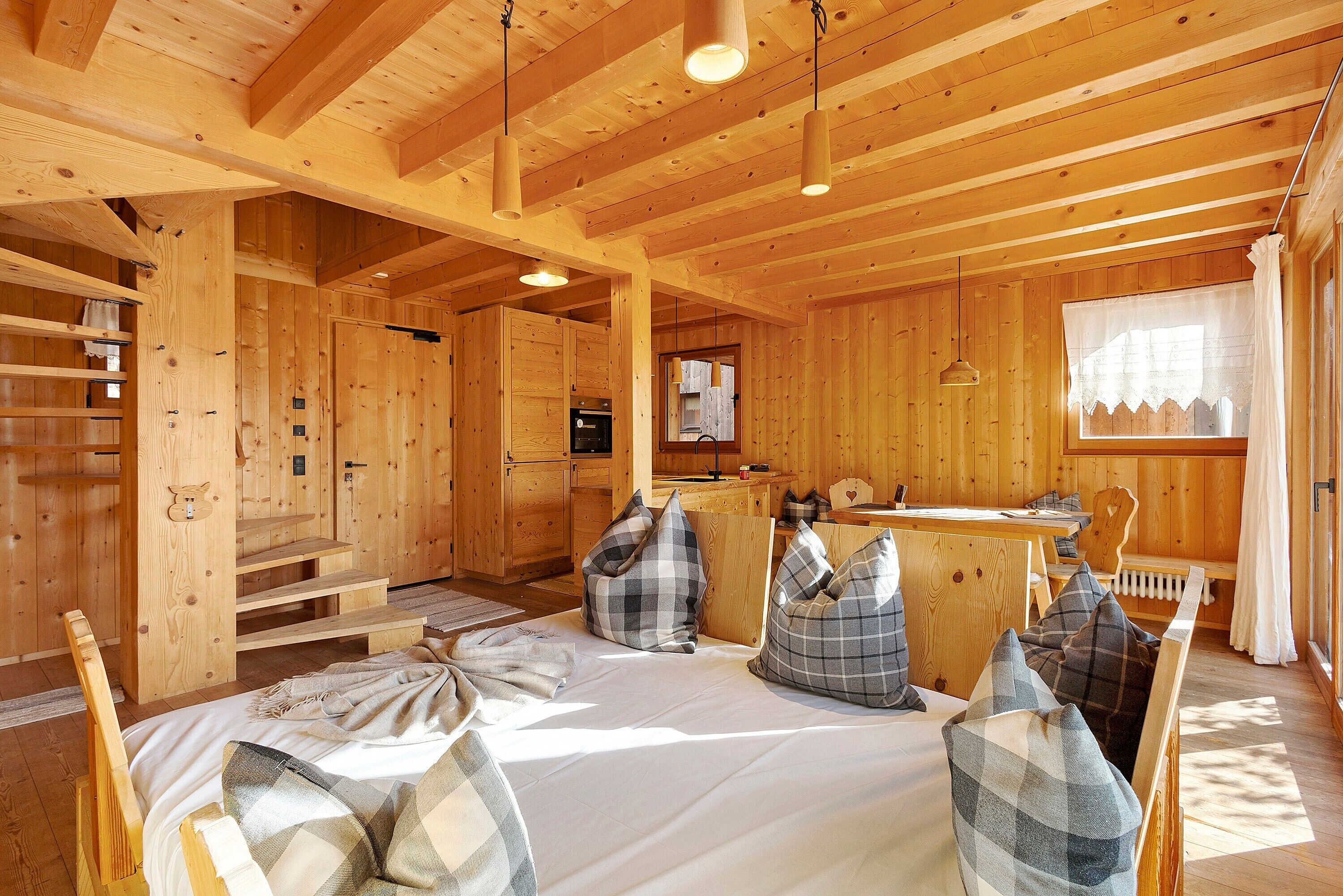 L’intérieur d’une cabane en bois comprend un lit, des oreillers, une table à manger et un coin cuisine.