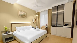 A hotel room with a large bed, bedside tables, a ceiling fan, a window with curtains, and a minibar. - Quad Hotels Hyderabad (Hyderabad)