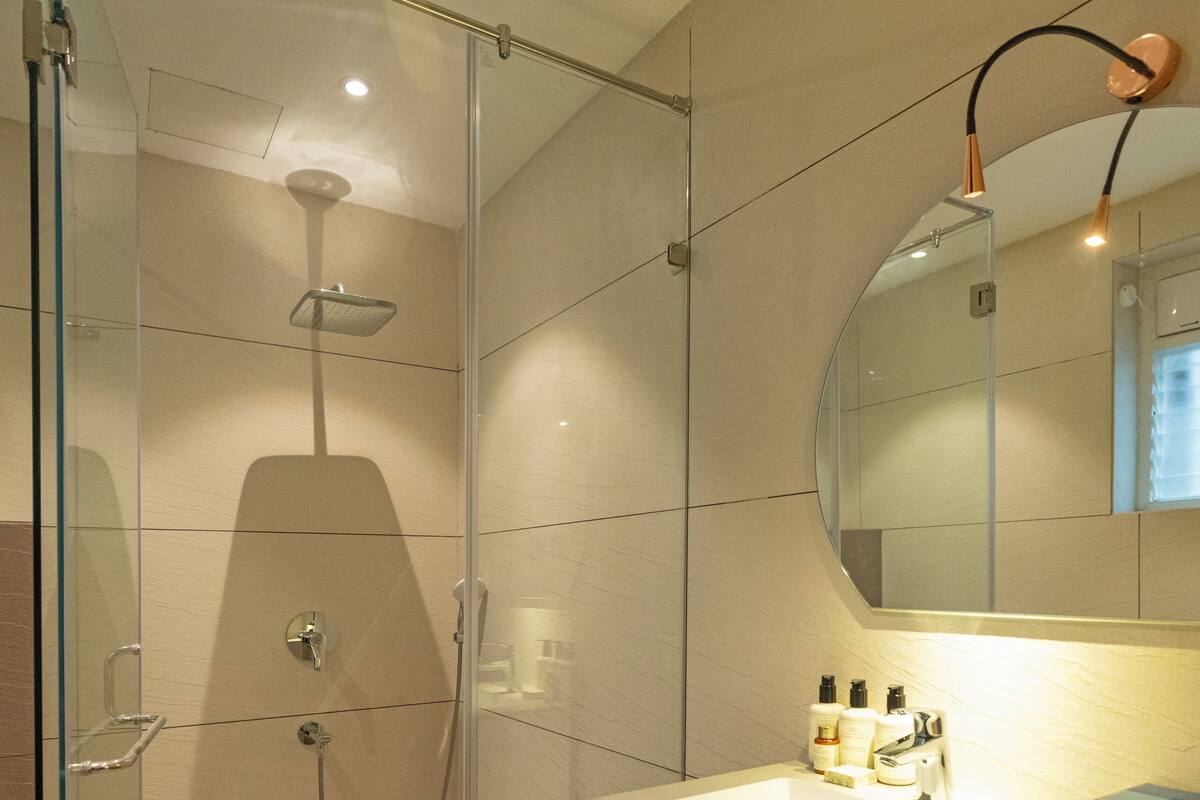 A modern bathroom with a glass-enclosed shower, a sink with a mirror above it, and a towel rack.