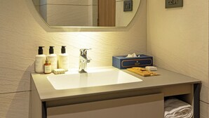 A modern bathroom with a round mirror, a sink, and toiletries. - Quad Hotels Hyderabad (Hyderabad)