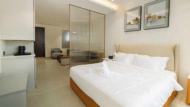 A hotel room with a large bed, a desk, a chair, and a sliding glass door leading to a balcony. - Quad Hotels Hyderabad (Hyderabad)