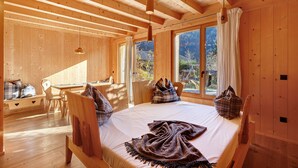 A wooden cabin with a bed, a desk, and a window overlooking a garden. - Chalet 'Groudo Michl 2' with Mountain View, Shared Terrace and Wi-Fi (Gsies)