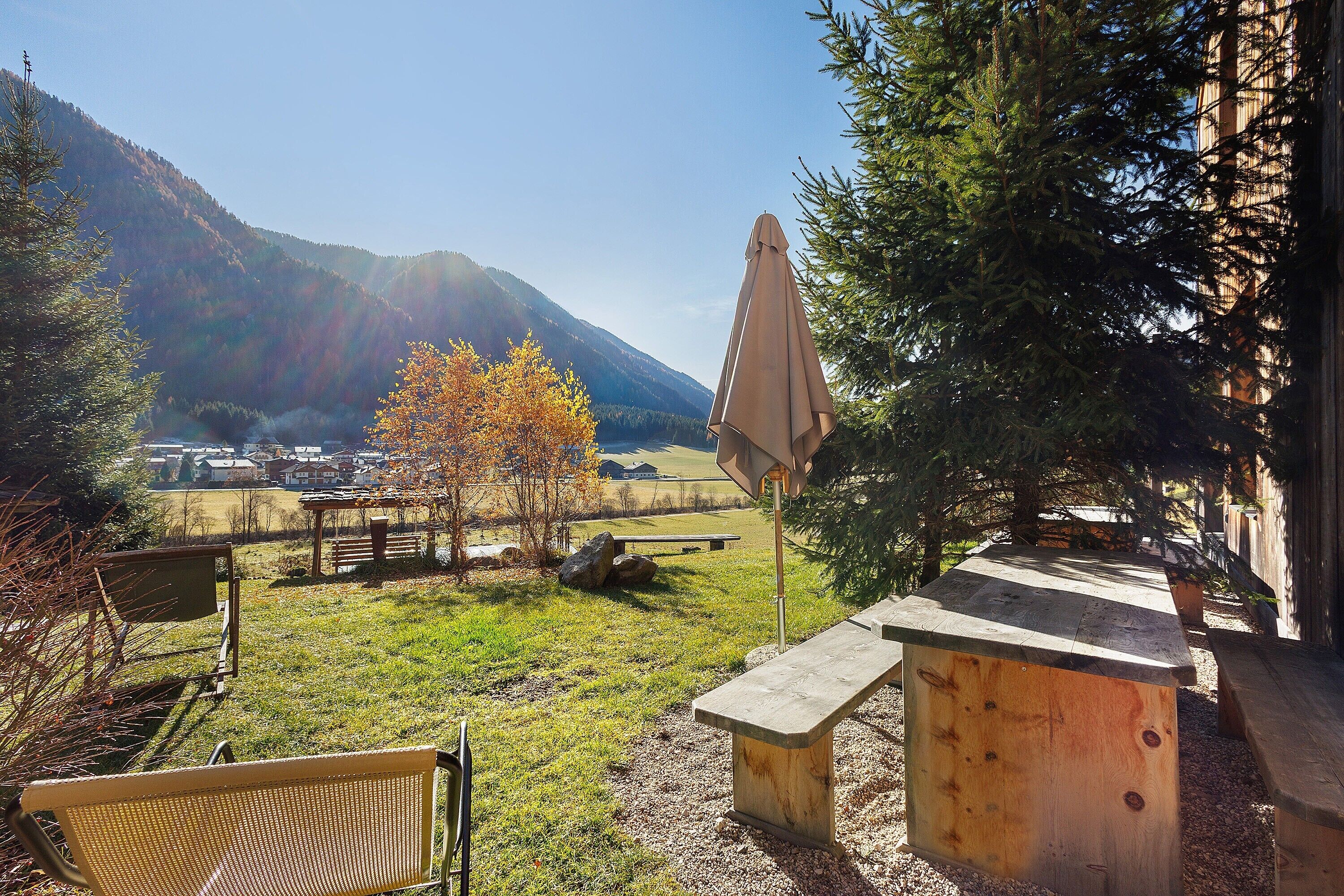 Un patio con una panchina, un tavolo e un ombrellone, con vista su un paesaggio montuoso.