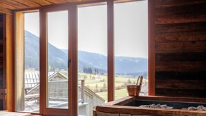 A wooden cabin with a stone fireplace, large windows with a view of mountains and a wooden deck. - Chalet 'Groudo Michl 2' with Mountain View, Shared Terrace and Wi-Fi (Gsies)