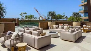 A rooftop lounge with sofas and chairs, a coffee table, and potted plants. - Ellington Beach House - Palm Jumeirah (Dubai)