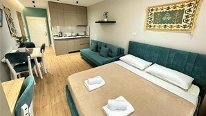Ein kompaktes Hotelzimmer mit Bett, Sofa, Essbereich und Küchenzeile.