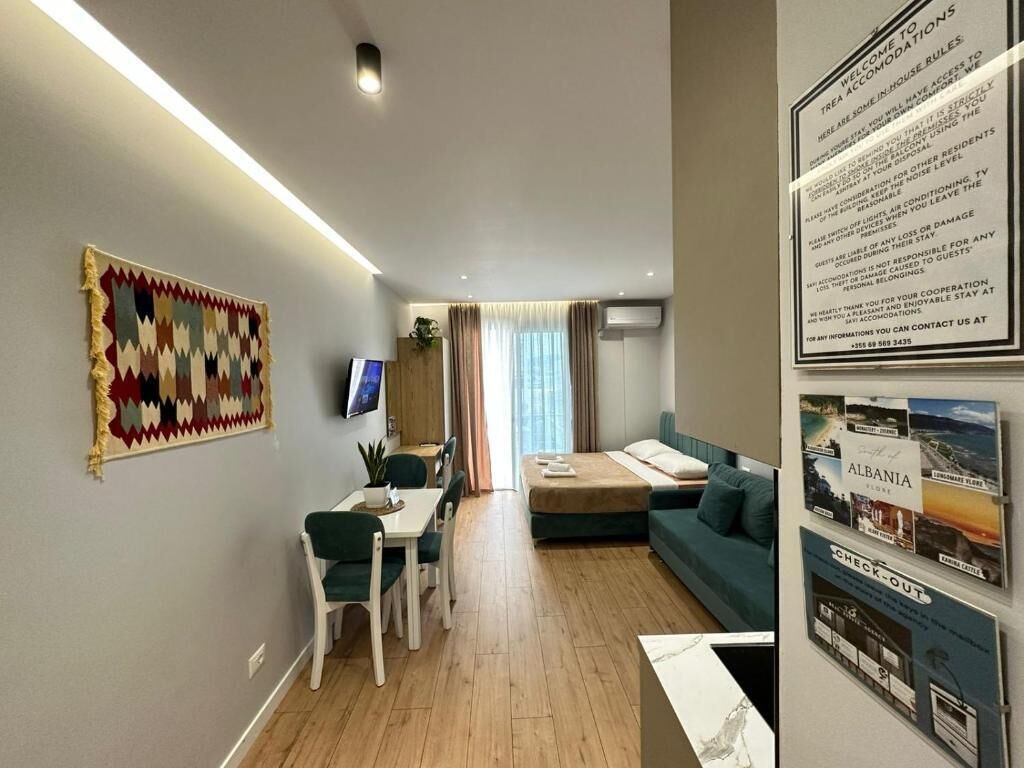 Een moderne woonkamer met een eethoek, een bank, een televisie en een muur met informatieposters.