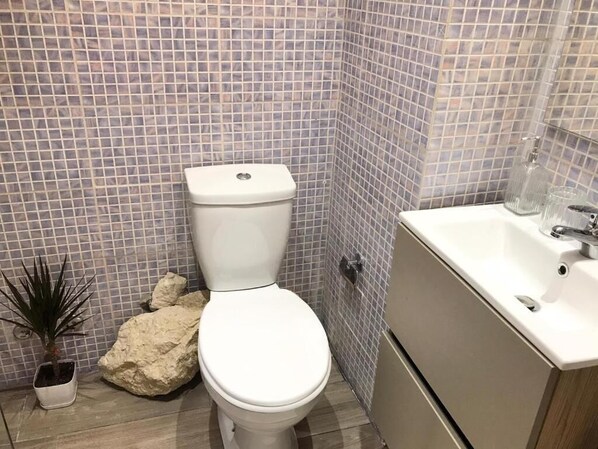 A bathroom with a toilet, sink, and tiled walls.
