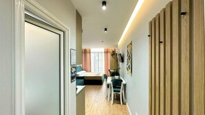 Ein Flur mit einer Holzpaneelausstattung, ein Essbereich mit Tisch und Stühlen sowie eine Sitzecke mit Sofa und Vorhängen.