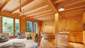 A wooden cabin with a bed, a dining table, and a kitchen area.
