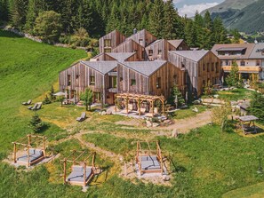 Un chalet rustique en bois, doté de plusieurs pièces, d’un jardin avec des meubles d’extérieur et offrant une vue pittoresque sur les montagnes.