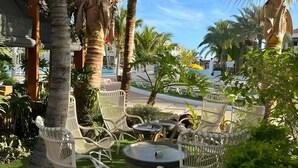 Espace extérieur aménagé avec des chaises et une table, entouré de palmiers et de verdure.