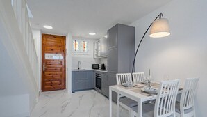 Une cuisine compacte avec un coin repas, une porte en bois et un luminaire suspendu moderne.