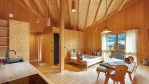 Ein Holzblockhaus-Innenraum mit Küche, Essbereich und einem Bett.