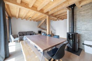 A modern interior with a wooden ceiling, a large table, and a fireplace.