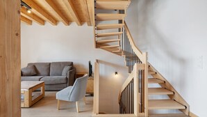 A modern interior with a wooden staircase, a grey sofa, and a wooden coffee table.