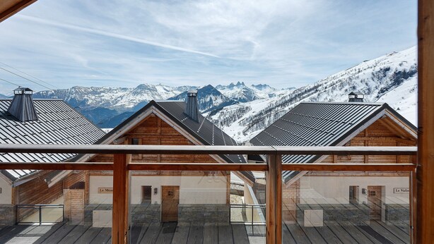 A wooden chalet with a view of snow-covered mountains.