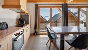 A modern kitchen with wooden cabinets, a stainless steel refrigerator, and a dining area with a table and chairs.