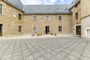 Un patio con paredes de piedra, piso de baldosas y una puerta central.