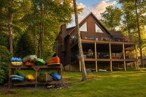 A two-story wooden cabin with a balcony, surrounded by trees.