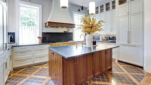 A modern kitchen with a central island, white cabinetry, and a patterned tile floor. - Downham House: Spacious 4BR, Old Town ALX (Alexandria)