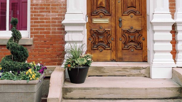 A brick building with a double wooden door, a small garden with potted plants, and a number plaque above the door. - Downham House: Spacious 4BR, Old Town ALX (Alexandria)