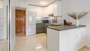 A modern kitchen with white cabinetry, a central island, and a wooden door.