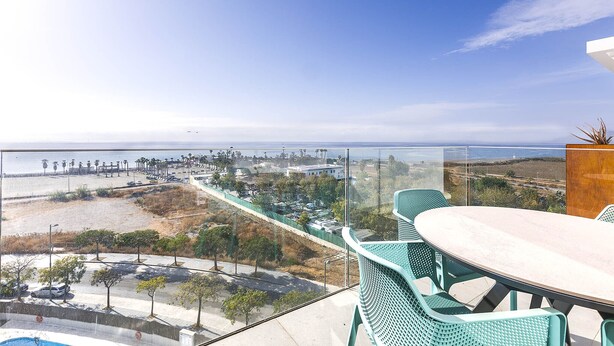 Ein Balkon mit Tisch und Stühlen mit Blick auf Strand und Stadtlandschaft.