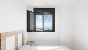 Ein Schlafzimmer mit Bett, Nachttisch und Fenster mit Meerblick.