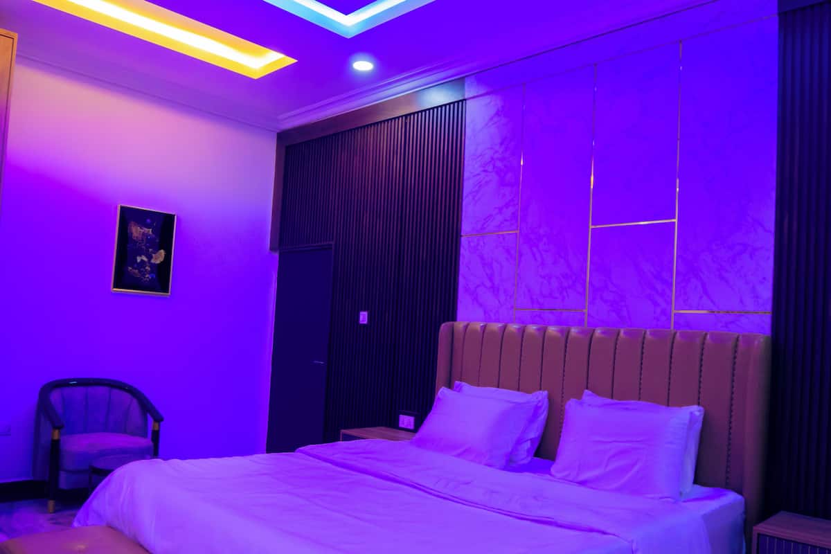 A modern bedroom with a bed, a chair, and a nightstand.