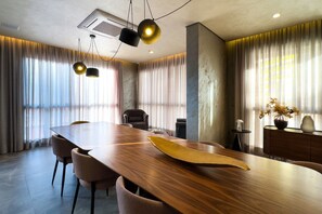 Ein Konferenzraum mit einem langen Holztisch, Stühlen und einer modernen Kronleuchter.