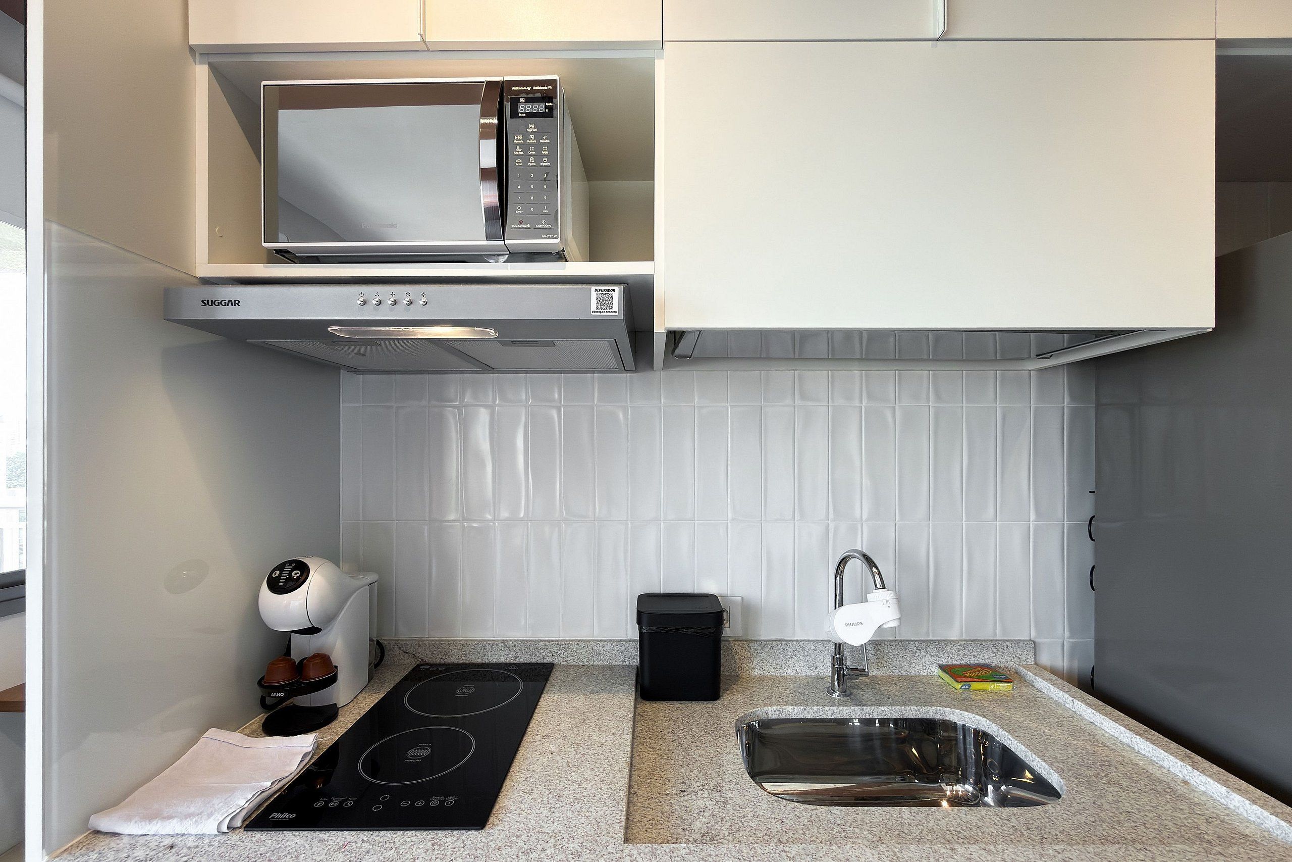 A kitchen with a microwave, stove, sink, and a coffee maker.