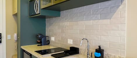 A kitchen with green cabinets, a granite countertop, a sink, and a built-in oven.