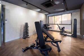 Ein Fitnessraum mit Krafttrainingsgeräten, einer Bank und einer Hantelbank.